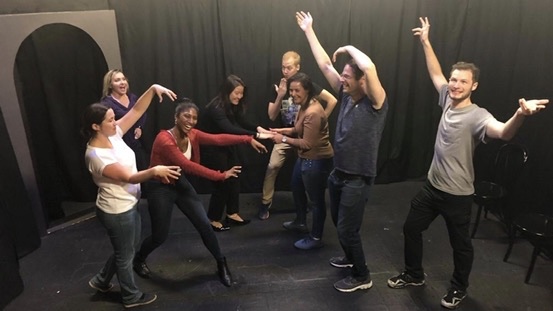 An improv ensemble responding to one another on stage.